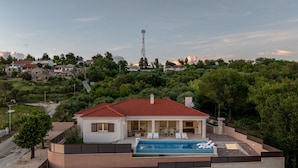 Une maison moderne avec une piscine, entourée de verdure et sous un ciel dégagé.