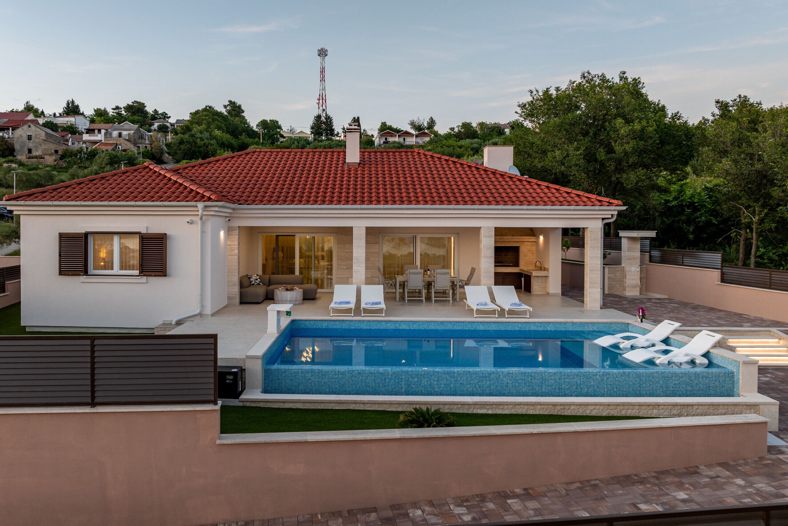 Una casa moderna con piscina, sillas de descanso y una zona de patio.