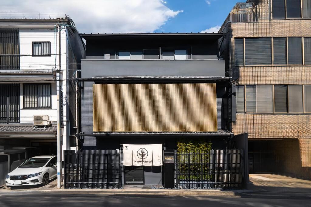 A modern building with a flat roof, a large vertical wooden panel, and a sign with Japanese characters.