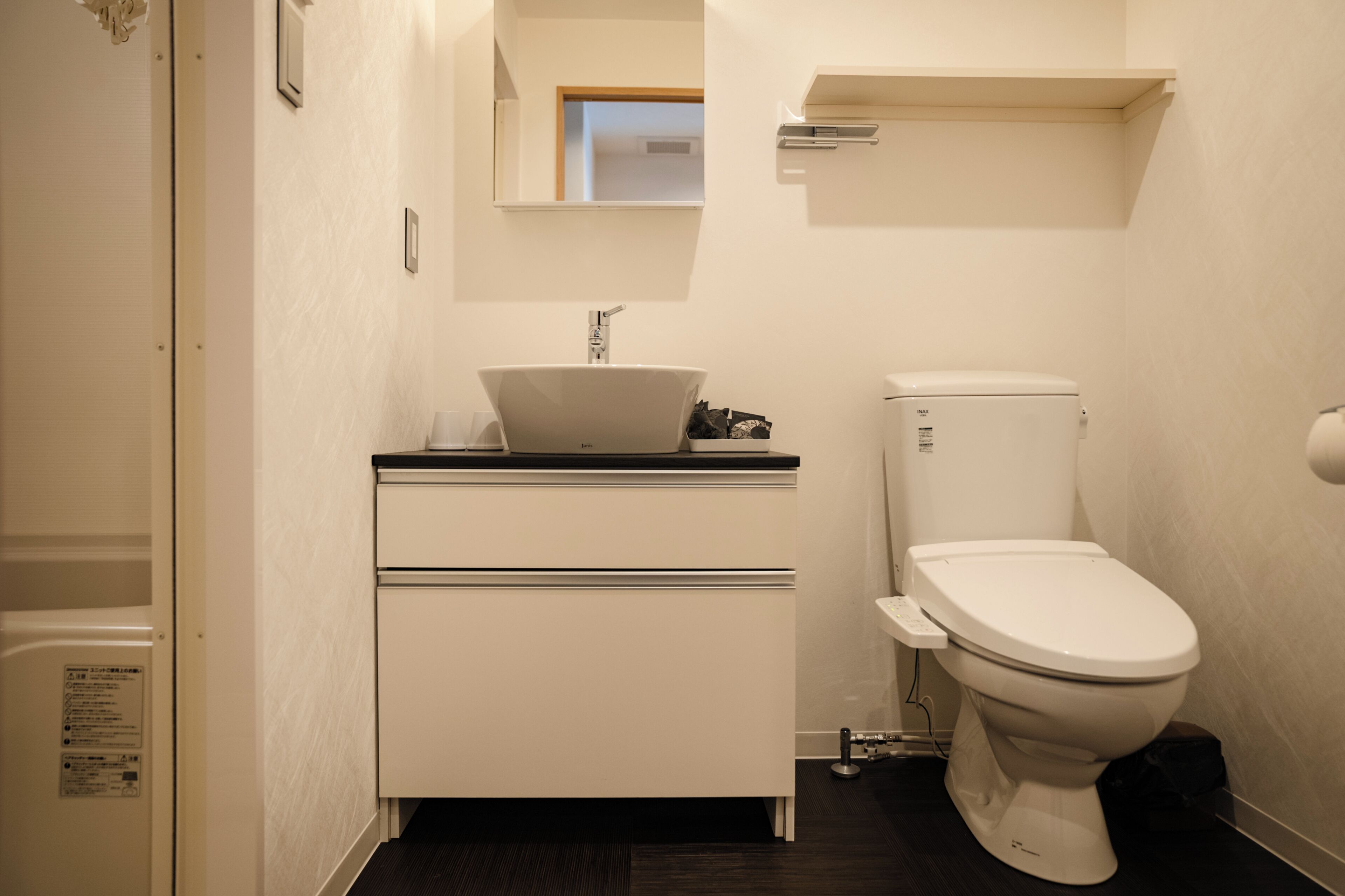 A bathroom with a white sink, toilet, and a mirror above the sink.