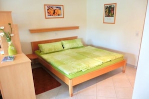 A bedroom with a bed, a desk, a chair, a vase with flowers, and two framed pictures on the wall. - Apartment in Rückholz with swimming pool (Rückholz)