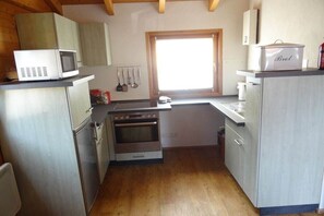 A compact kitchen with a microwave, oven, and a window. - At the lake, the "Hüttle" (Bräunlingen-Unterbränd)