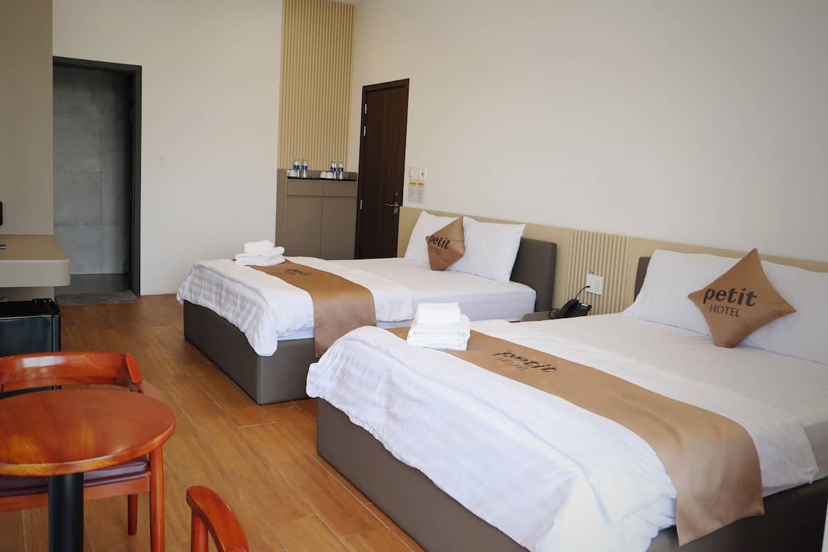 Une chambre d’hôtel avec deux lits, une table en bois et un bureau avec une chaise.