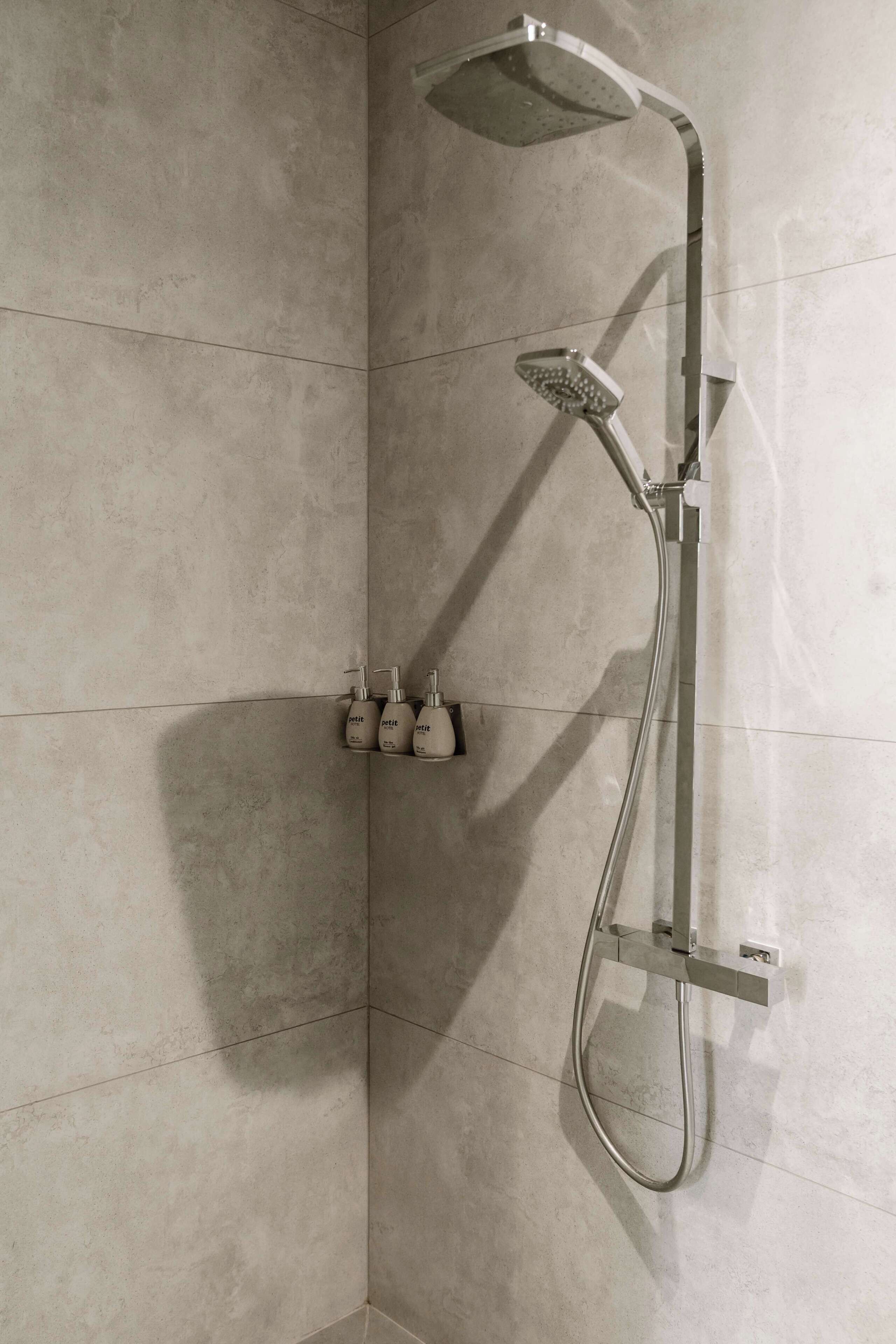Een douchehoek met een handdouche en een bedieningspaneel aan de wand.