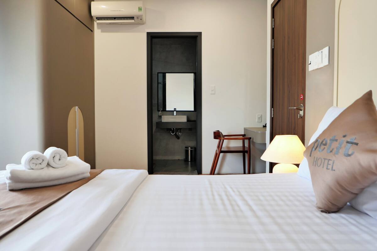Une chambre d’hôtel équipée d’un lit, d’une chaise, d’un bureau, d’un miroir, d’un lavabo et d’un porte-serviettes.