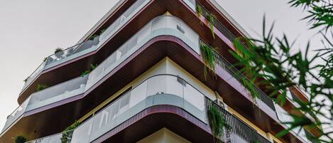Un edificio de varios pisos con balcones, algunos con plantas.