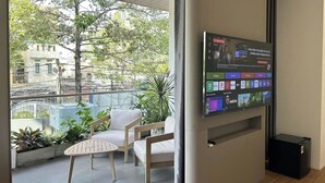 Un balcón con una pantalla de televisión mostrando diversas aplicaciones, una silla blanca y una pequeña mesa.