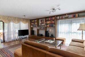 Ein Wohnzimmer mit einer Couch, einem Couchtisch, einem Fernseher und Bücherregalen.