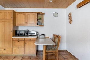 Une cuisine avec des meubles de rangement en bois, un four à micro-ondes, un grille-pain et une horloge au mur.