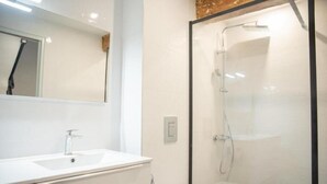 Ein modernes Badezimmer mit einer Glastrennwand-Dusche, einem weißen Waschbecken und einer Toilette.