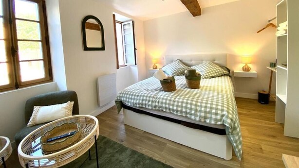 Ein Schlafzimmer mit Bett, Stuhl, Nachttisch, Spiegel und Kleiderschrank.