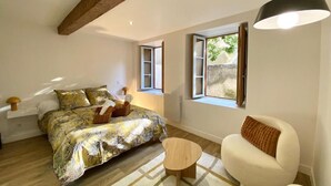 Ein Schlafzimmer mit einem Bett, einem kleinen Tisch, einer Couch und einem Fenster mit Vorhängen.