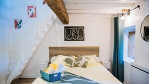 Ein Schlafzimmer mit einem Bett, einem hölzernen Kopfteil, einem kleinen Nachttisch, einer Wandleuchte, einem Spiegel und einer Treppe.