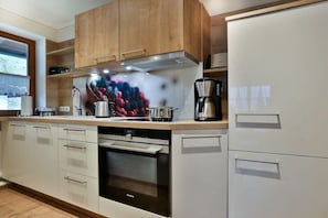 Eine moderne Küche mit Holzausstattung, einem eingebauten Ofen und einer Kaffeemaschine.