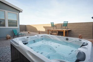 A hot tub with two chairs, a table, and a building in the background. - Gorgeous Strip View House with Telescope and Hot Tub (Henderson)