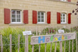 Un senyal de fusta amb la inscripció 'Hofacker', un edifici amb persianes vermelles i un altre senyal que diu 'Gerste'.