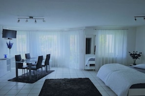Ein Hotelzimmer mit einem Bett, einem Schreibtisch mit Stühlen, einem Fernseher und einem Badezimmer.
