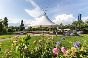 Ein Pavillon mit einem kegelförmigen Dach, umgeben von einem Rundweg und üppiger Vegetation.