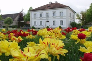 A white building with a symmetrical facade, multiple windows, and a central entrance. - Holiday apartment with 1 bedroom (Bad Füssing)