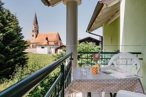 A balcony with a table, chairs, and a view of a church. - Holiday apartment with 1 bedroom (Bad Füssing)