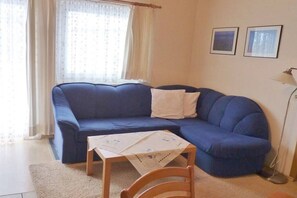 Ein Wohnzimmer mit einem blauen Sofa, einem kleinen Tisch und einer Lampe.