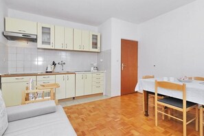 Eine kleine Küche mit weißen Schränken, einem Holztisch und einer Couch.