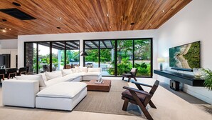 A modern living room with a sectional sofa, a coffee table, and a TV. - Casa Ventura Luxury Villa Golondrinas Hacienda Pinilla Costa Rica (Tamarindo)