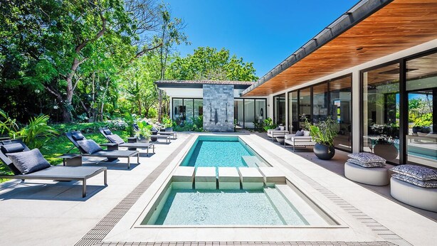 A modern outdoor pool area with lounge chairs and a stone structure. - Casa Ventura Luxury Villa Golondrinas Hacienda Pinilla Costa Rica (Tamarindo)
