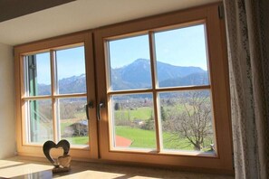 A room with a large window offering a view of mountains and a green landscape. - Jochberg holiday apartment (Bad Reichenhall)