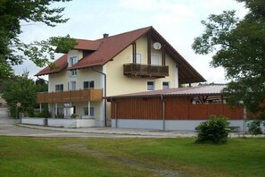 Ein zweistöckiges Haus mit Balkon, Garage und einem kleinen Garten.