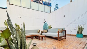 Uma área externa com assentos, um deck de madeira, um sofá e plantas em vasos.