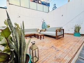 Un área de estar al aire libre con terraza de madera, un sofá y plantas en macetas.