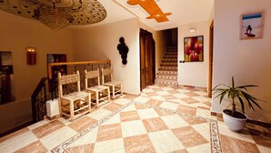 Um hall com piso xadrez, escada e obra de arte na parede.