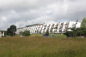 Ein mehrstöckiges Wohngebäude mit moderner Architektur, mit Balkonen und einer flachen Dachfläche.