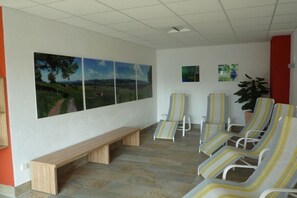 Ein Wartebereich mit einer Bank, gestreiften Lounge-Sesseln und einer Wand mit Landschaftsbildern.