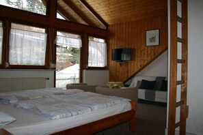 Ein Schlafzimmer mit Holzboden, einem Bett, einem Fernseher und einer Treppe.