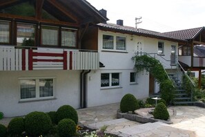 Ein zweistöckiges Gebäude mit einem Balkon, einer Steinterrasse und einer Treppe.