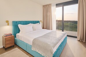 Una camera da letto con un letto grande, un comodino con libri, vista attraverso una grande finestra e un balcone.