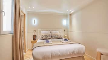 A bedroom with a large bed, bedside tables, a window with curtains, and a nightstand with a lamp.