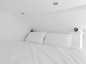 Ein helles Schlafzimmer mit einem Bett, einer Deckenleuchte und einer Wandlampe.