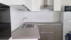 Une cuisine moderne dotée d’appareils électroménagers en acier inoxydable, d’un évier encastré et d’un four à micro-ondes placé sur le dessus du réfrigérateur.