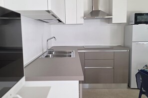 Eine moderne Küche mit Edelstahlgeräten, einer eingebauten Spüle und einer Mikrowelle auf dem Kühlschrank.