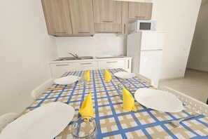 A kitchen with wooden cabinets, a microwave, and a refrigerator. - Appartment in Rosolina Mare (RO) (Rosolina Mare (RO))