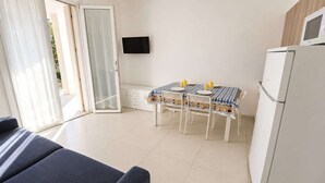 Una habitación con una mesa de comedor, sillas, televisor y refrigerador.