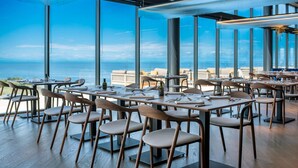 A restaurant with tables and chairs arranged indoors, overlooking a scenic view.