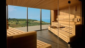 A modern interior with wooden furniture, large windows, and a view of the sea.