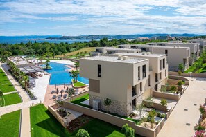 Un hotel moderno con piscina, zona de estar al aire libre y vista al mar.