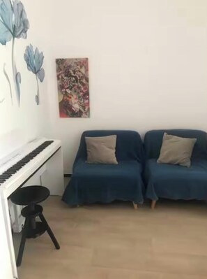 Un salon avec un piano, deux canapés et un tableau accroché au mur.