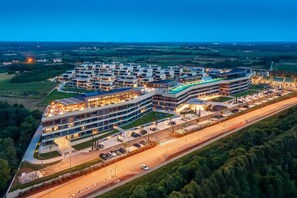 Un hotel moderno con diversi piani, un’area parcheggio e una piscina.