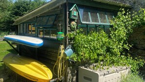 A rustic cabin with a small porch, a birdhouse, and a kayak.